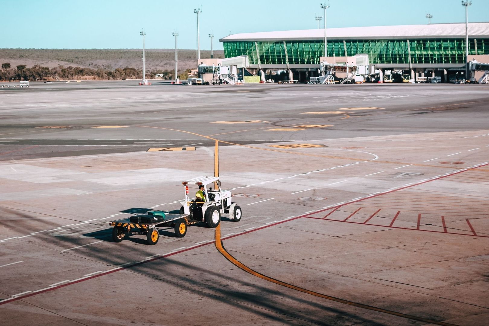 Bagagetrekker met kar op het platform bij een luchthavenhal