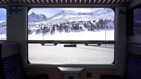 Uitzicht vanuit een trein op besneeuwde Alpenbergen