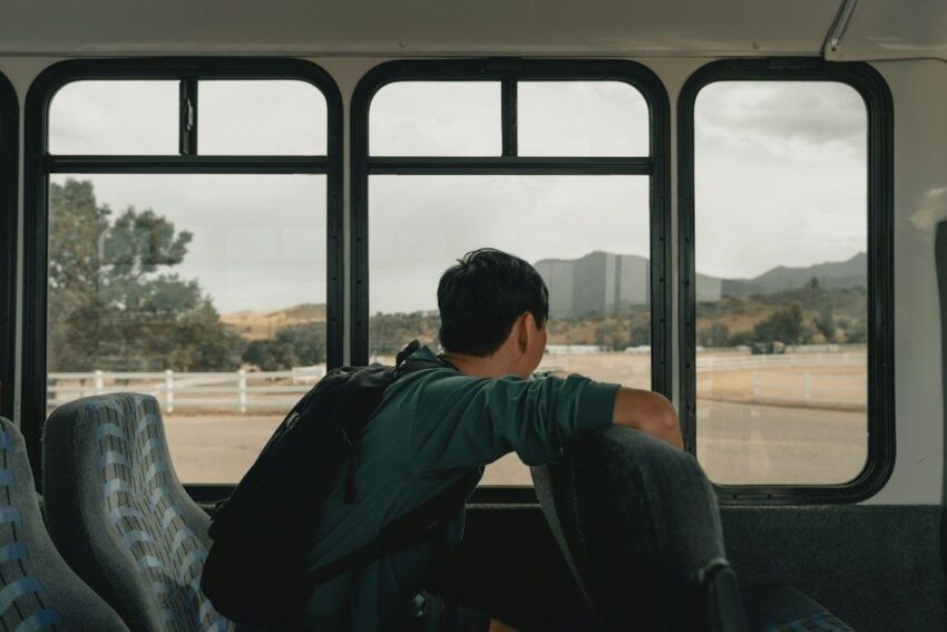 Reiziger met rugzak kijkt vanuit een bus naar het Duitse landschap